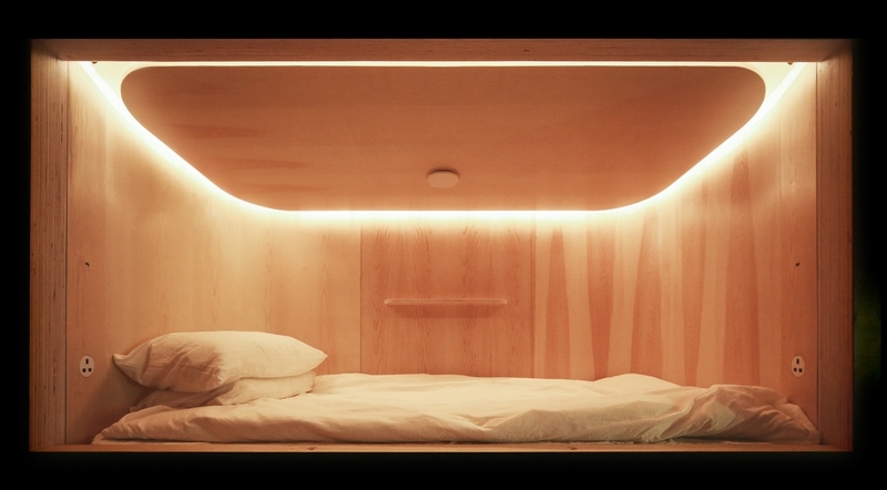 A warmly lit, private nap pod with fresh linens, ready for a nap.